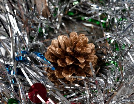 Close up of a single gold pine cone in silver tinsel for the holiday season 