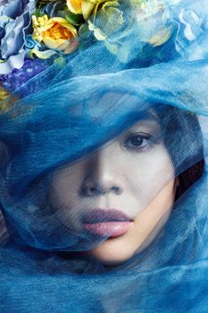 portrait of asian beautiful woman with floral hat and blue veil on light grey background, closeup