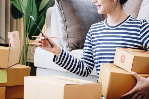 Business ideas for selling products online, beautiful girls are checking products that customers order from documents in order to pack products into parcel boxes to deliver to customers.