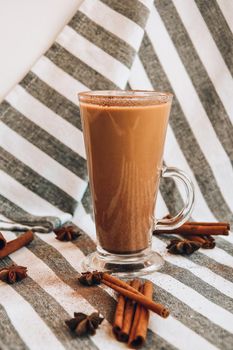 Delicious iced coffee and milk melt drink, cinnamon sticks and anise stars on gray cloth