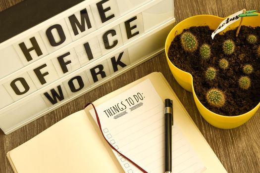 lightbox with text HOME OFFICE WORK with notebook pen and cactus and TO DO list, copy space wooden table background, quarantine and isolation HOME OFFICE