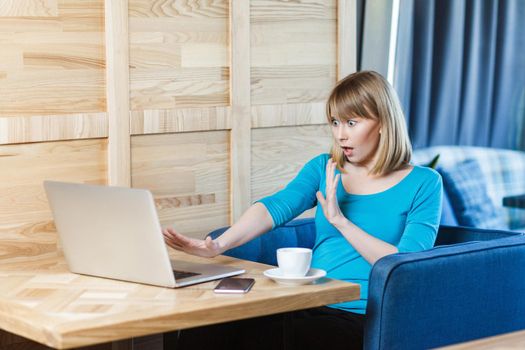 Emotional worker woman in blue shirt sitting and working on computer