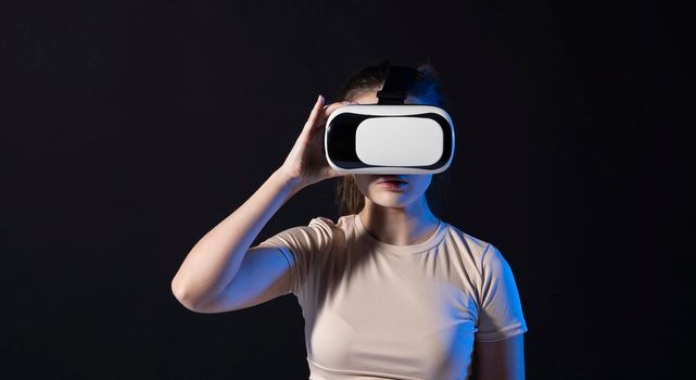 Young beautiful woman wearing a VR headset and experiencing a virtual reality simulation, metaverse and cyberspace concept.