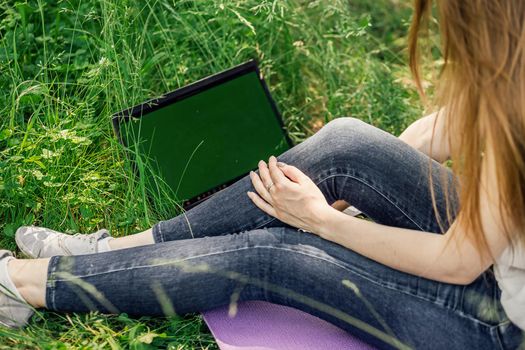girl sits on the grass and works at a laptop. freelance. selfeducation. the concept of distance learning outdoors.