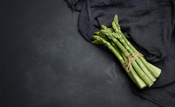 Fresh green asparagus sprouts on a black background. View from above