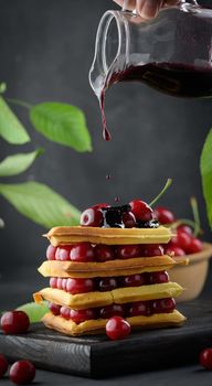 A stack of baked Belgian waffles with ripe red cherries