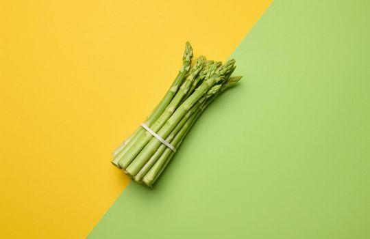 Bunch of fresh asparagus on green paper background