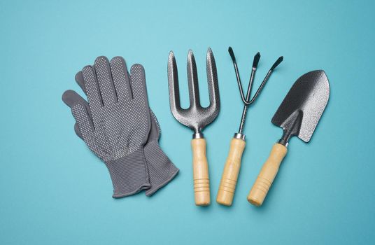 Garden tools for processing beds in the garden and textile gloves on a blue background