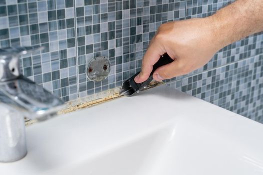 dirty grouts in the bathroom and moldy tiles. master cleans dirt with a tool