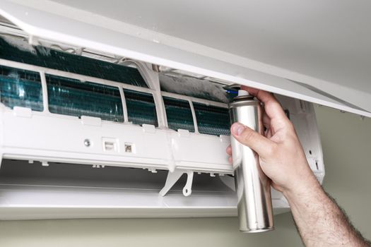 Male technician cleaning air conditioner indoors