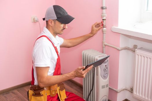 The technician checking the heating system with tablet in hand