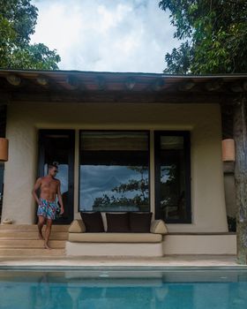 European man at infinity pool looking out over the ocean, luxury vacation , private pool villa