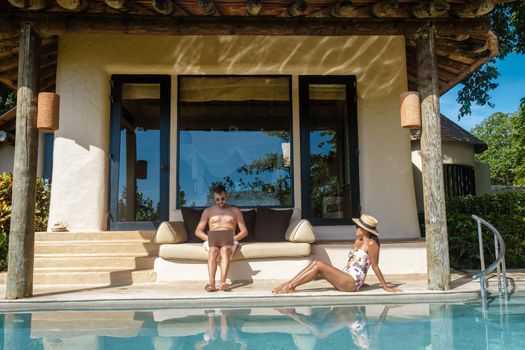 remote online working digital nomad men and women and laptop sitting pool at a private pool villa,
