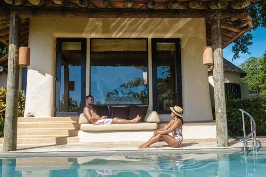 remote online working digital nomad men and women and laptop sitting pool at a private pool villa,