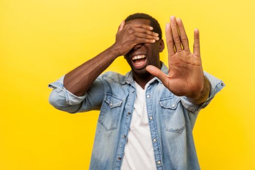 Young emotional man on yellow background.
