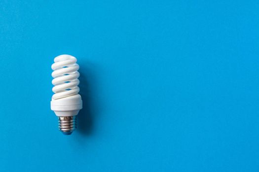 Energy saving light bulb on a blue background. Economical consumption of electricity. The concept of nature conservation