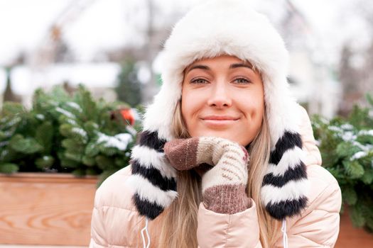 Winter portrait young adult beautiful blonde woman wearing funny fluffy hat. Christmas mood. Snowing winter beauty fashion concept