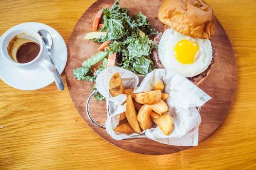 Fried egg and salad. Egg salad sandwich with French fries. The salad with homemade baked French fries, grilled steal hard-boiled eggs, poached eggs. Fast food breakfast