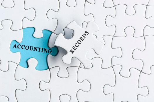 Accounting records text on blue background of white jigsaw puzzle.