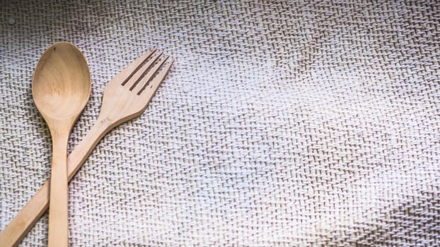 wooden spoon and fork on sack bag background with copyspace