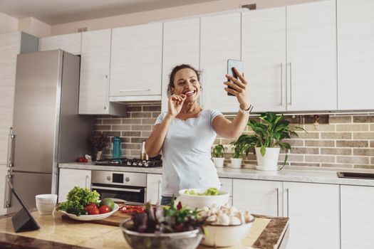 A housewife takes a selfie on her phone camera while preparing a salad