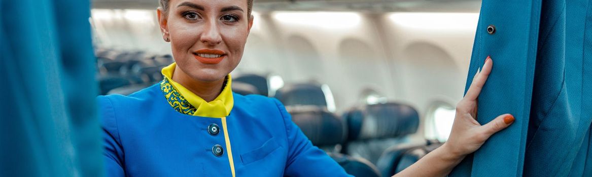 Joyful woman stewardess standing in passenger aircraft cabin