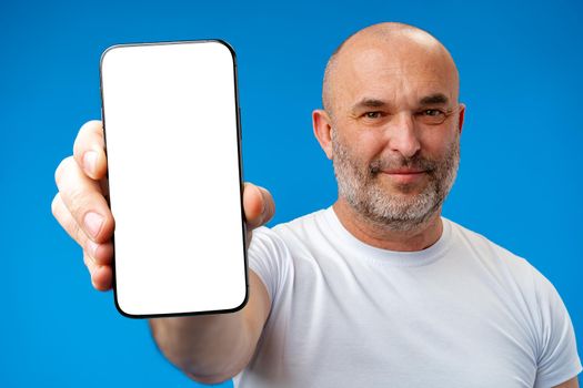 Middle-aged man showing blank smartphone screen with copy space against blue background