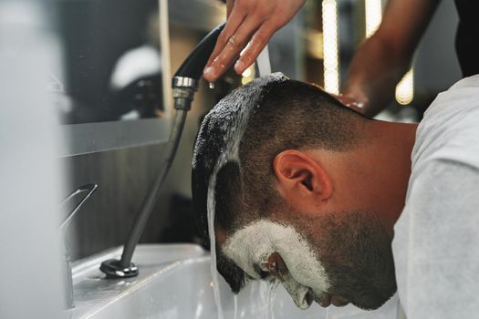 Hairdresser man washes client head in barbershop, close up