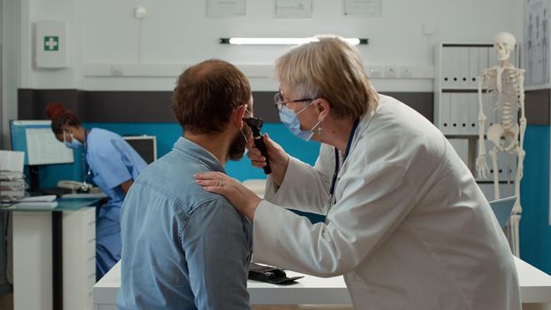 Doctor otologist examining ear infection of patient with otoscope