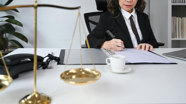 Cropped shot of middle aged female lawyer working and notary signs the documents at personal office. Lawyer, justice and law and attorney concept