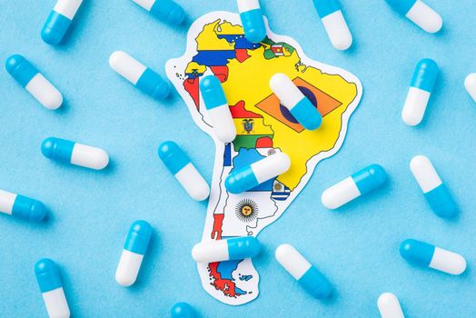 Many medical pills, capsules on top of map and flag of South America Continent