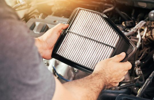 A auto mechanic holding car air filter