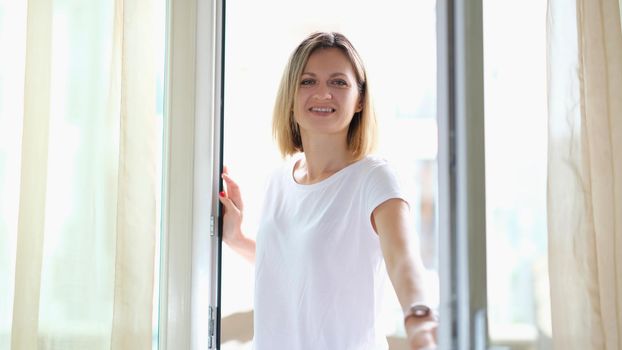 Beautiful smiling woman opens a glass door