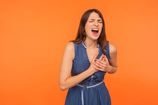 Portrait of young emotional woman on orange background.