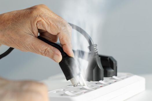 Elderly hand with electrical outlet spark