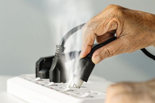 Elderly hand with electrical outlet spark