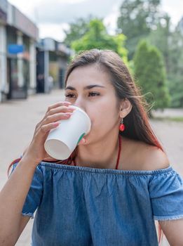 Stylish millennial woman drinking coffee at street cafe in summer