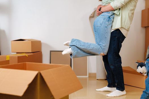 Young happy couple in room with lots of moving boxes