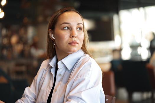 Portrait of a blonde woman in white shirt sitting in cafe