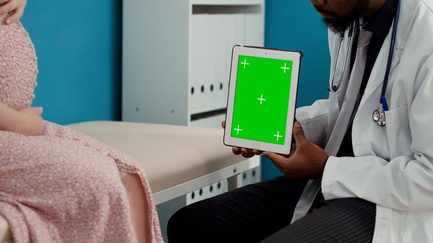 Male medic working with greenscreen on tablet at examination