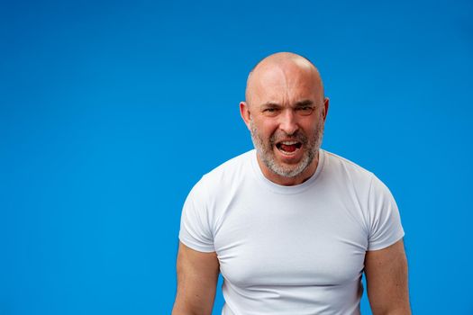 Frustrated bearded man shouting and screaming against blue wall