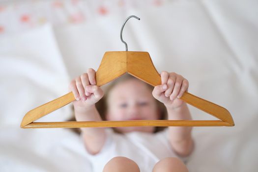 Child is holding wooden clothes hanger closeup