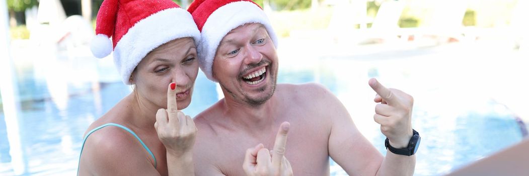 Man and woman in santa claus hats show fucking gesture into monitor