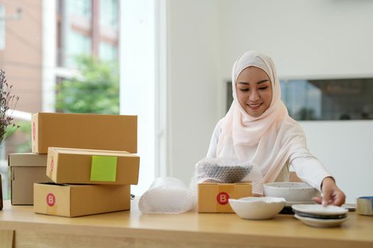 SME freelance woman muslim working with packaging startup entrepreneur small business owner at home,Online business seller packaging and delivery concept.