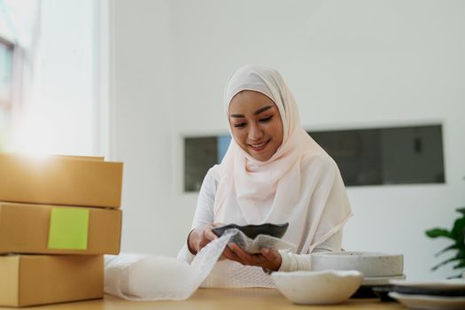 Asian muslim owner packing products preparing toshopping and make arrangements for delivery online while he works at home..