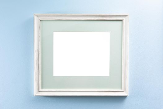 wooden picture frame with passe-partout on a blue wall, copy-space background
