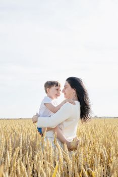 Happy family of mother and infant child walking on wheat field, family portrait