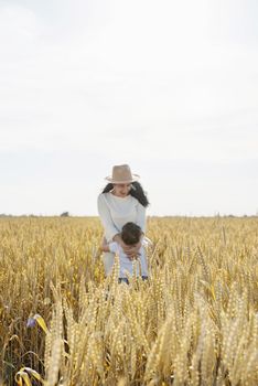 Happy family of mother and infant child walking on wheat field