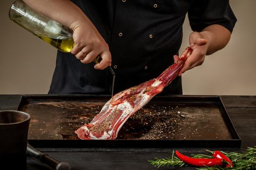 Male chef pouring lamb shank with oil. Chef cooking appetizing shank of lamb.