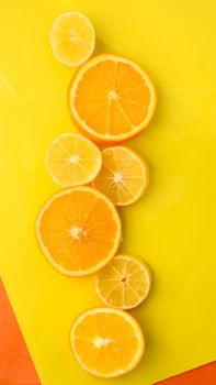 Orange and lemon slices on the yellow background - stock photo